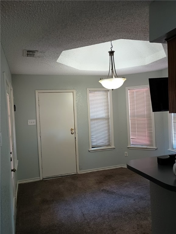 unfurnished dining area featuring dark carpet and a textured ceiling