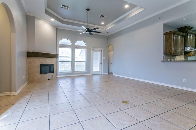 unfurnished living room with a raised ceiling, ceiling fan, crown molding, and light tile patterned flooring