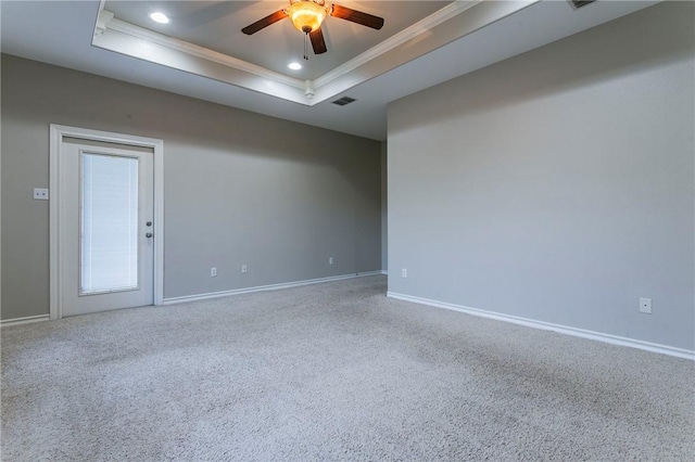 carpeted empty room featuring a raised ceiling, crown molding, and ceiling fan