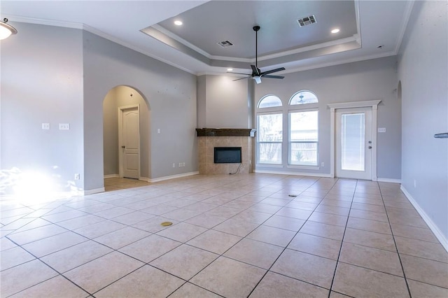 unfurnished living room with ceiling fan, a raised ceiling, ornamental molding, and light tile patterned floors