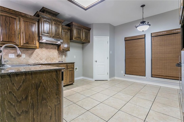 kitchen with dark brown cabinetry, sink, dark stone countertops, decorative backsplash, and light tile patterned floors