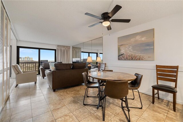 tiled dining space with a textured ceiling and ceiling fan