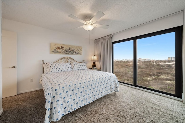 carpeted bedroom featuring ceiling fan and a textured ceiling