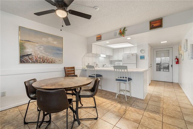 tiled dining room featuring ceiling fan and a textured ceiling