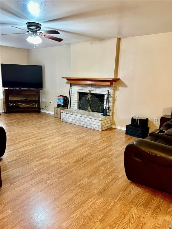 living room with a brick fireplace, light hardwood / wood-style floors, and ceiling fan