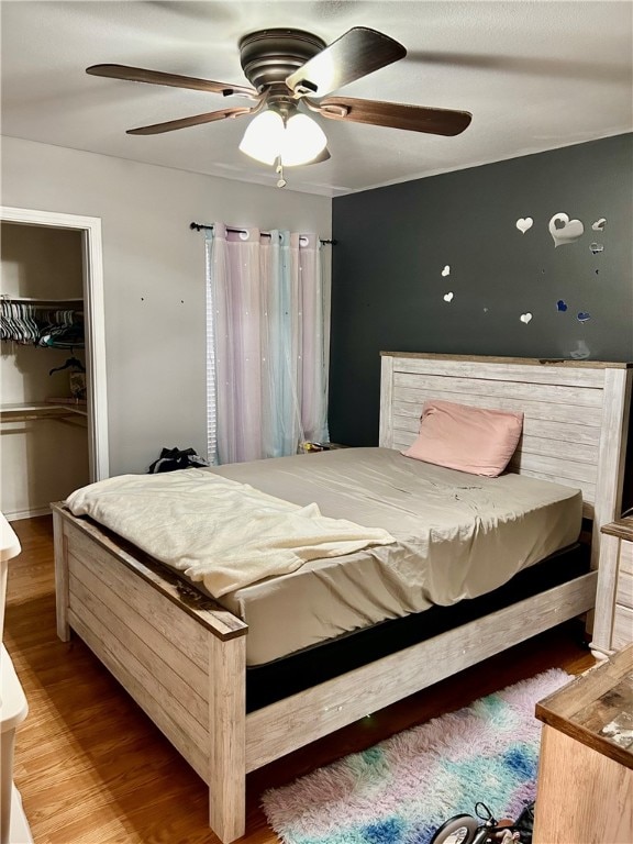 bedroom featuring wood-type flooring, ceiling fan, and a closet