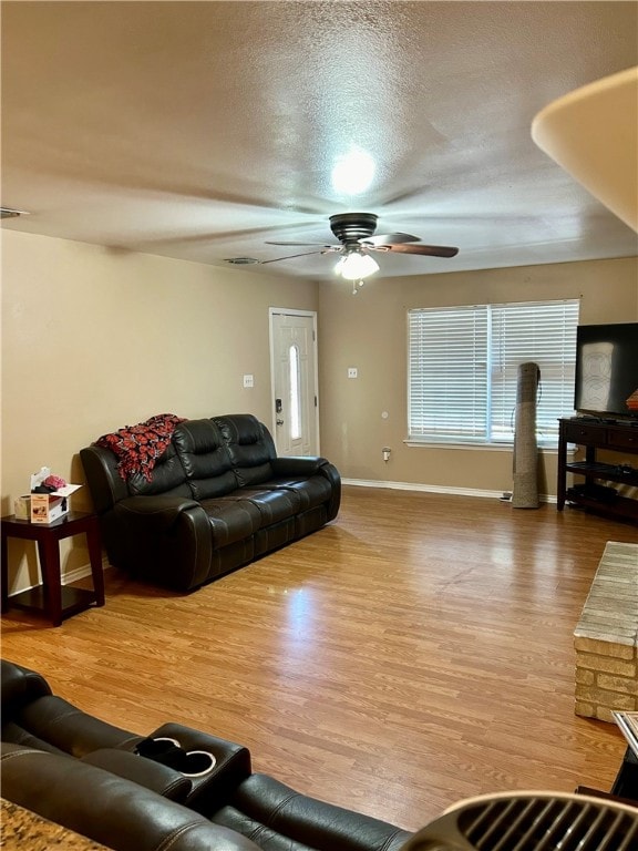 living room with a textured ceiling, hardwood / wood-style flooring, and ceiling fan