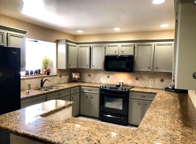 kitchen featuring decorative backsplash, black appliances, sink, and light stone counters