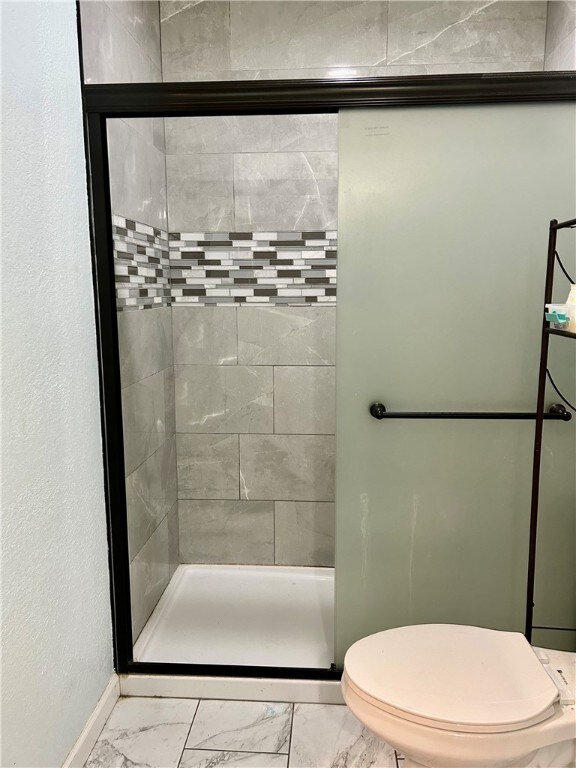 bathroom with toilet and tiled shower