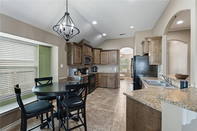 kitchen with black appliances, backsplash, a notable chandelier, sink, and vaulted ceiling