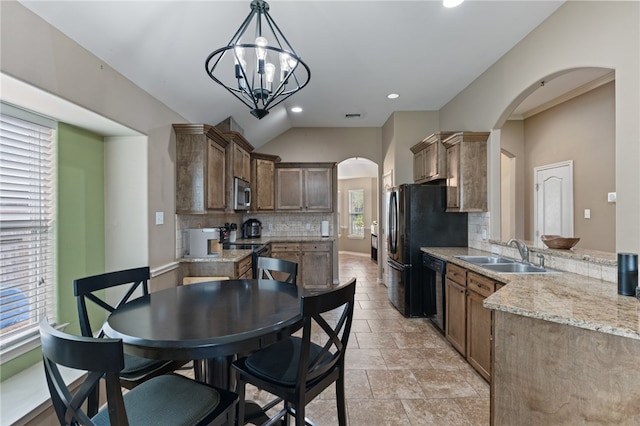 kitchen with decorative light fixtures, a wealth of natural light, black appliances, and tasteful backsplash