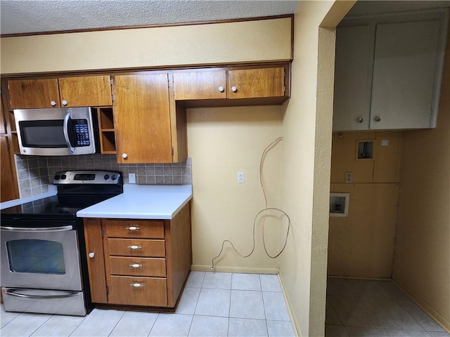 1662 Spicewood Dr, Corpus Christi, TX 78412 - kitchen featuring brown cabinets, backsplash, appliances with stainless steel finishes, and light tile patterned floors
