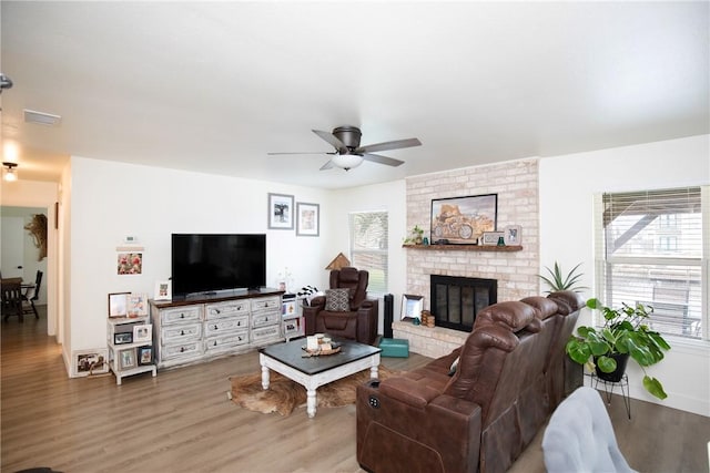 living room featuring ceiling fan, a wealth of natural light, hardwood / wood-style flooring, and a fireplace