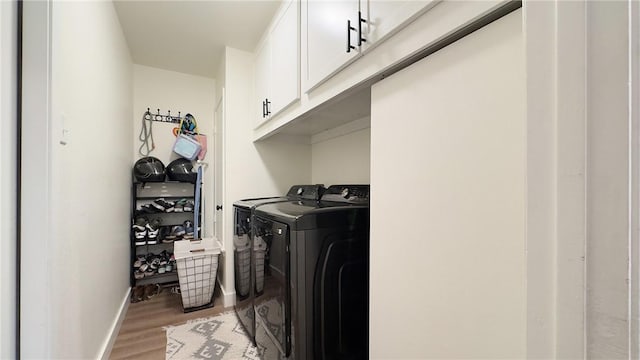 laundry area featuring washer and dryer, cabinets, and light hardwood / wood-style flooring