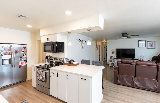 kitchen with pendant lighting, a kitchen bar, white cabinetry, stainless steel appliances, and ceiling fan