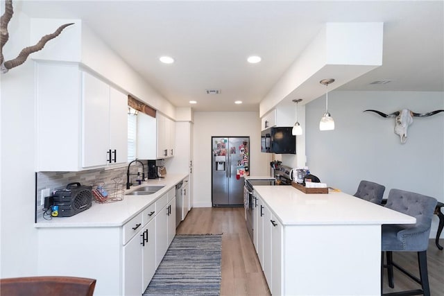 kitchen with hanging light fixtures, a breakfast bar area, sink, and white cabinetry