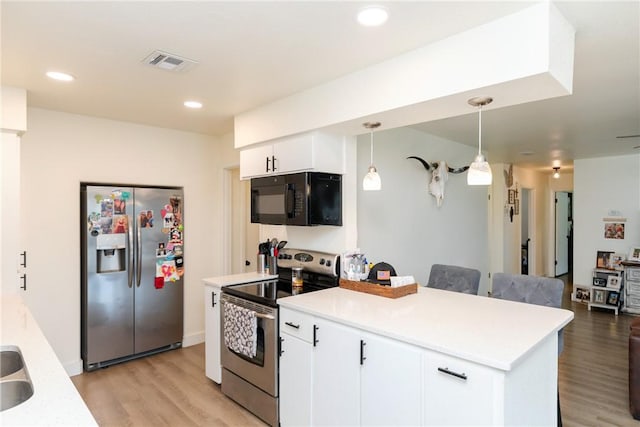 kitchen with white cabinetry, appliances with stainless steel finishes, pendant lighting, light hardwood / wood-style flooring, and a breakfast bar