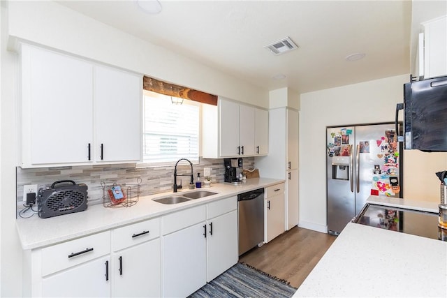 kitchen featuring white cabinetry, stainless steel appliances, tasteful backsplash, light hardwood / wood-style floors, and sink