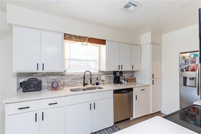 kitchen featuring decorative backsplash, appliances with stainless steel finishes, sink, and white cabinetry