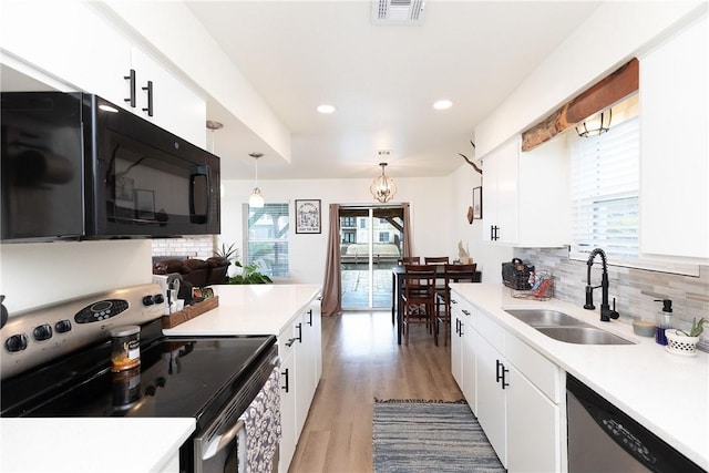 kitchen with decorative light fixtures, white cabinets, sink, and stainless steel appliances