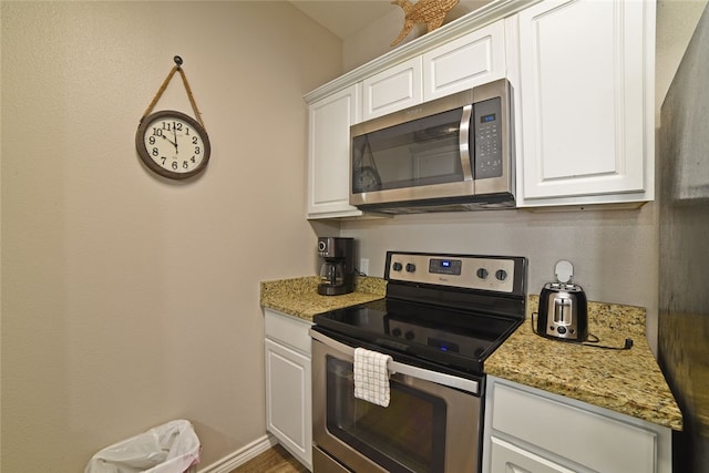 kitchen with white cabinets, stainless steel appliances, and light stone counters