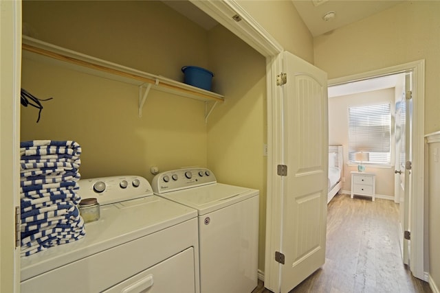 laundry room with washing machine and dryer and light hardwood / wood-style flooring