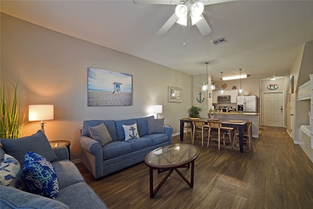 living room with ceiling fan with notable chandelier and dark hardwood / wood-style flooring