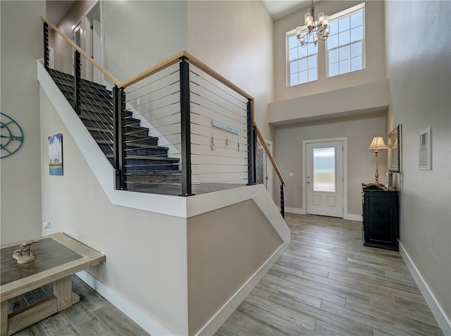 entrance foyer with light hardwood / wood-style flooring, a towering ceiling, and a notable chandelier