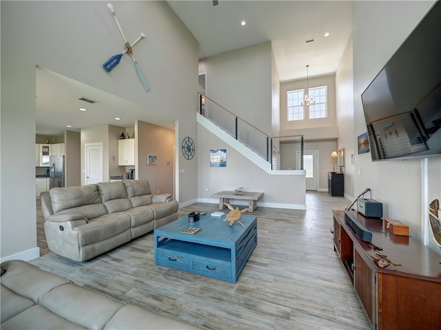 living room featuring a notable chandelier, light hardwood / wood-style floors, and a high ceiling