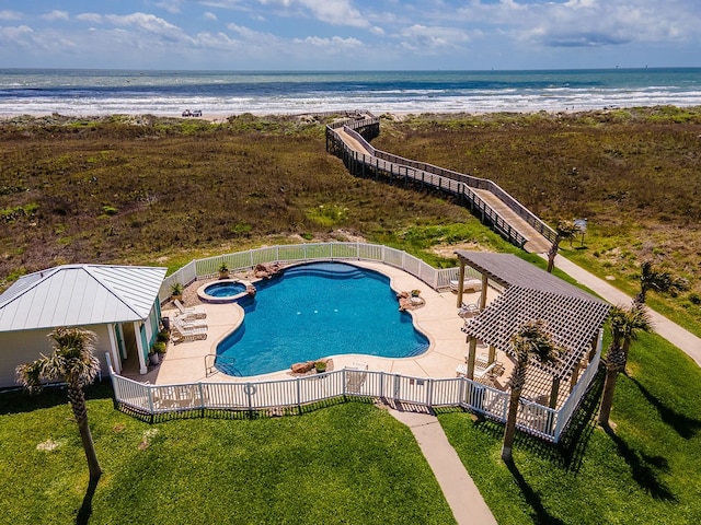 view of swimming pool featuring an in ground hot tub, a water view, a patio, and a view of the beach