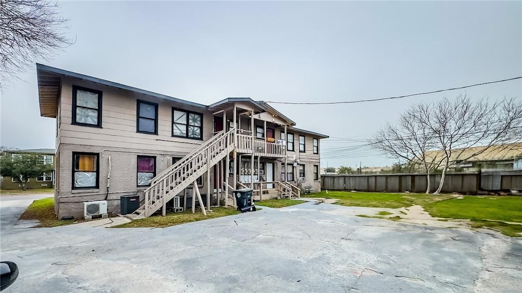 back of house featuring ac unit, a yard, and central AC