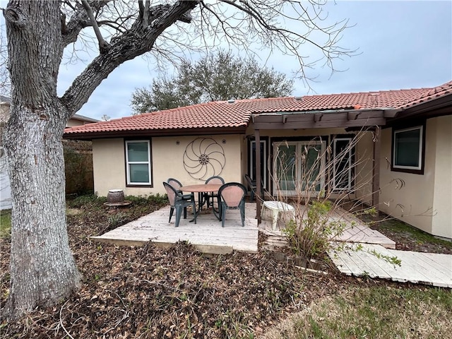 rear view of property featuring a patio, a tiled roof, and stucco siding