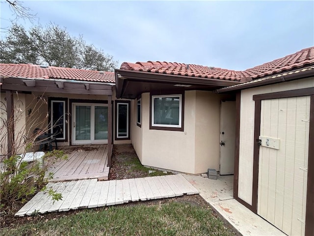 back of property featuring a wooden deck, stucco siding, and a tile roof