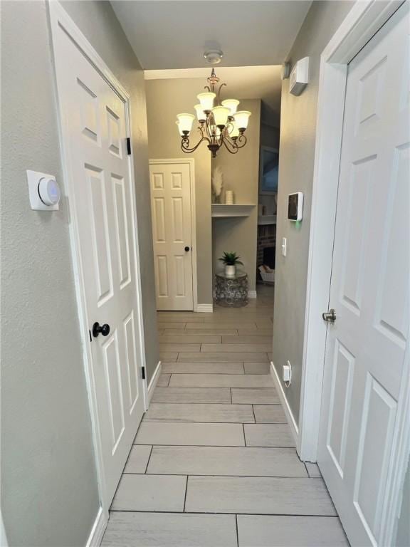 corridor with an inviting chandelier, baseboards, and wood finish floors