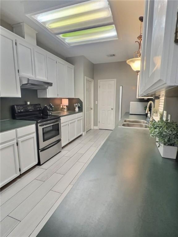 kitchen featuring white cabinetry, a sink, under cabinet range hood, and stainless steel electric range