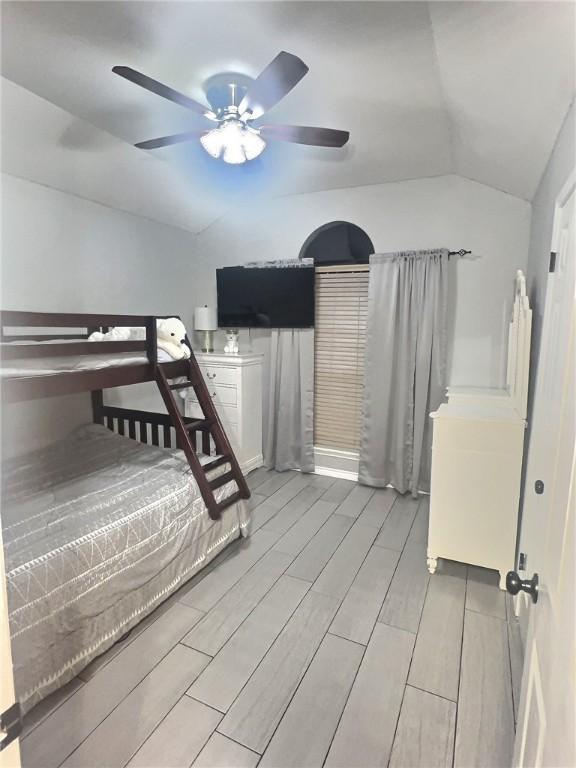 unfurnished bedroom featuring a ceiling fan, lofted ceiling, and wood finish floors