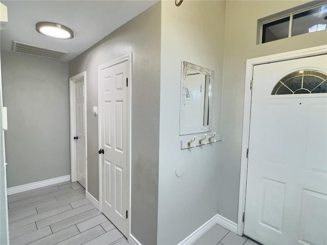 foyer entrance with baseboards, visible vents, and wood finish floors