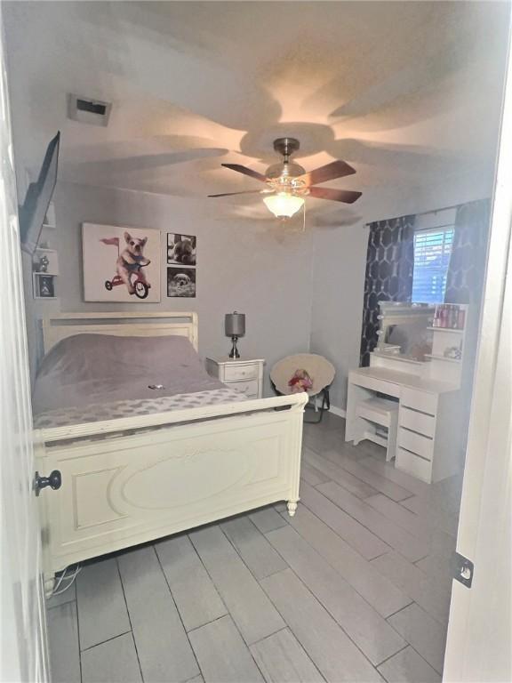 bedroom featuring ceiling fan, visible vents, and wood tiled floor