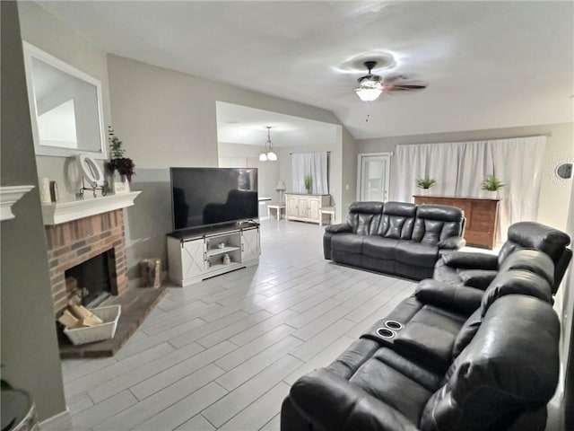 living area featuring light wood-style floors, a brick fireplace, and a ceiling fan