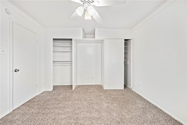 unfurnished bedroom with a textured ceiling, ornamental molding, two closets, ceiling fan, and carpet