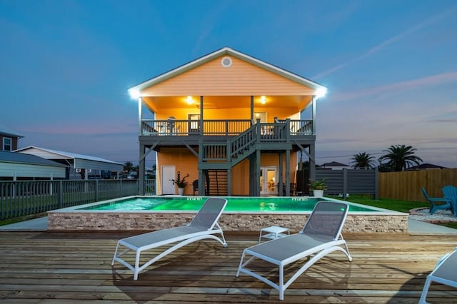 back house at dusk featuring a swimming pool side deck