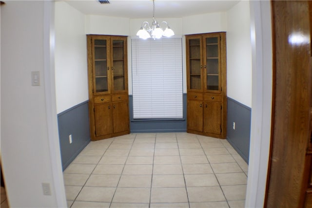 unfurnished dining area with an inviting chandelier and light tile patterned floors