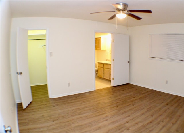 unfurnished bedroom featuring light hardwood / wood-style floors, ensuite bath, ceiling fan, a closet, and a spacious closet