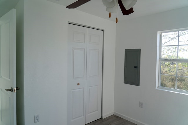 unfurnished bedroom featuring multiple windows, dark hardwood / wood-style flooring, electric panel, and a closet