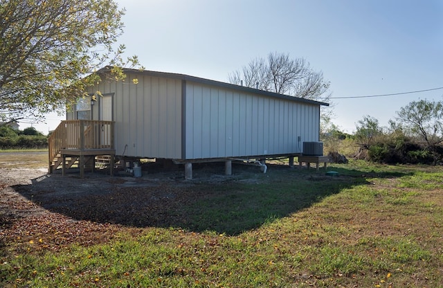 view of outbuilding featuring central AC unit and a lawn