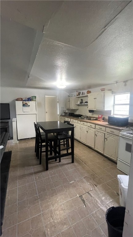 kitchen with light tile patterned flooring, white cabinetry, sink, a textured ceiling, and white appliances