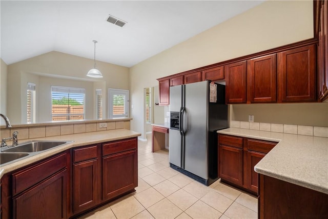 kitchen featuring light countertops, hanging light fixtures, reddish brown cabinets, visible vents, and fridge with ice dispenser