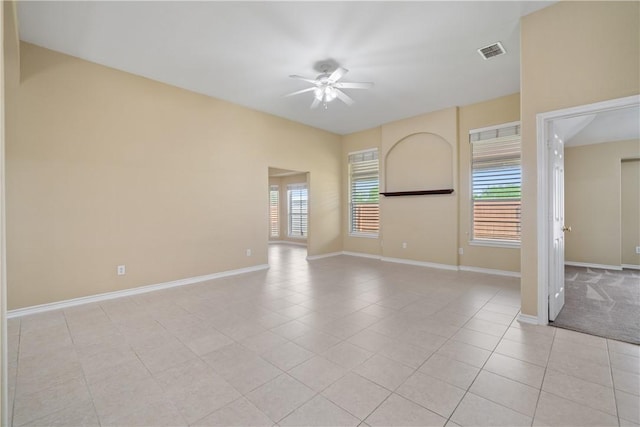 empty room featuring baseboards, ceiling fan, visible vents, and light tile patterned floors