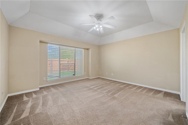 carpeted spare room with a tray ceiling, baseboards, vaulted ceiling, and a ceiling fan