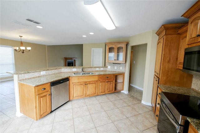 kitchen with stainless steel appliances, backsplash, a sink, light stone countertops, and a peninsula